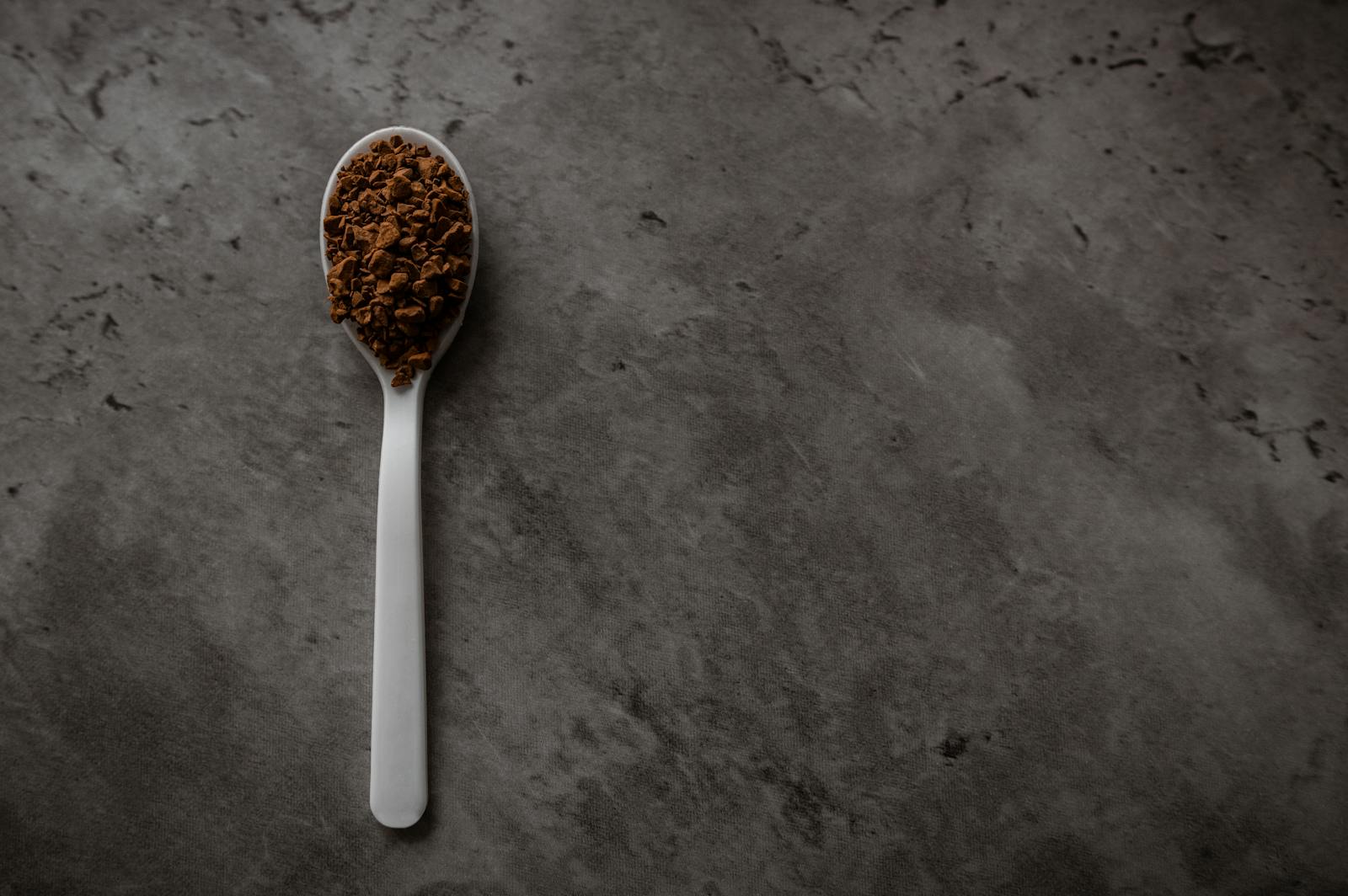 Spoon holding instant coffee granules above a cup