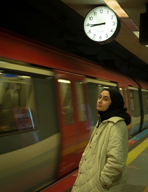 Free Woman in a headscarf waiting at İstanbul train station platform with a clock above. Stock Photo