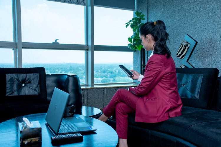 Woman In Pink Suit Sitting On Couch In Office