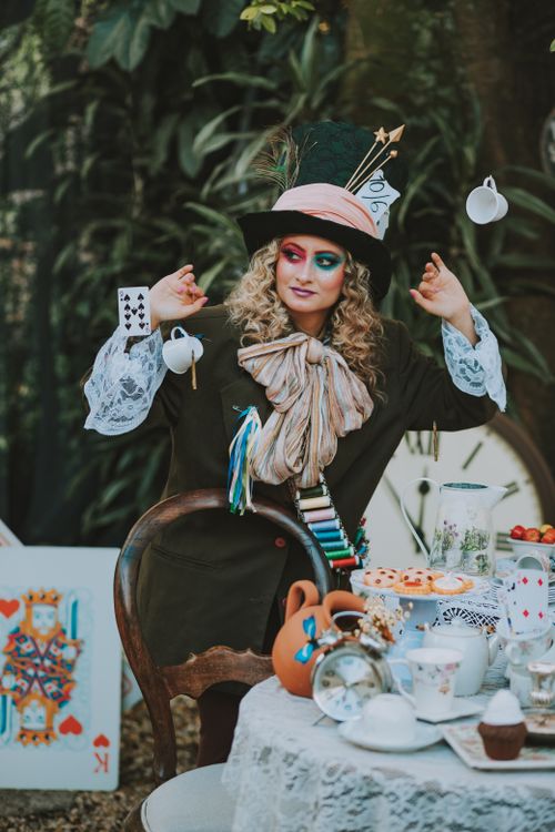 Free A fantasy cosplay portrait depicting a young woman as the Mad Hatter with a whimsical tea party setup. Stock Photo
