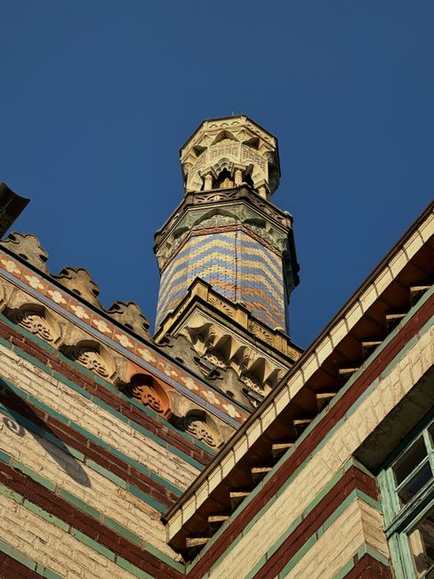 Low angle view of a colorful minaret under a clear blue sky, showcasing intricate designs.