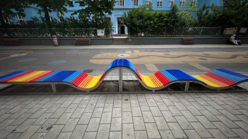 Free Wave-shaped bench with rainbow colors on a lively urban street, adding a pop of color. Stock Photo