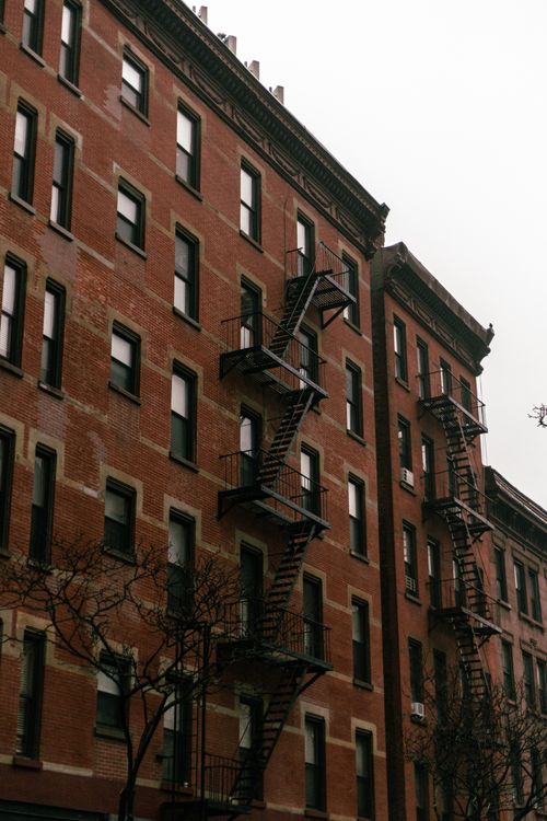 Free Brick residential building featuring traditional fire escapes and windows. Stock Photo