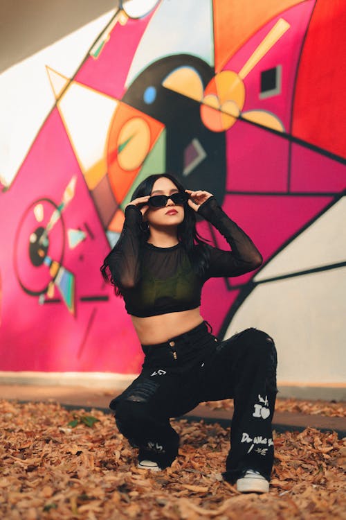 Woman in Sunglasses Crouching on Autumn Leaves