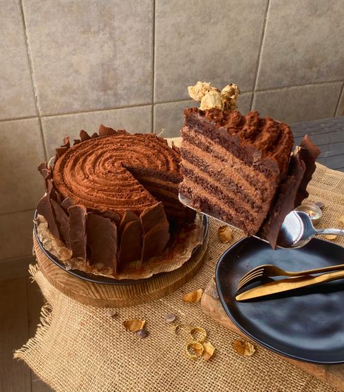 Free Delicious multi-layered chocolate cake with a slice removed, showcasing intricate details and garnished with dried flowers. Stock Photo