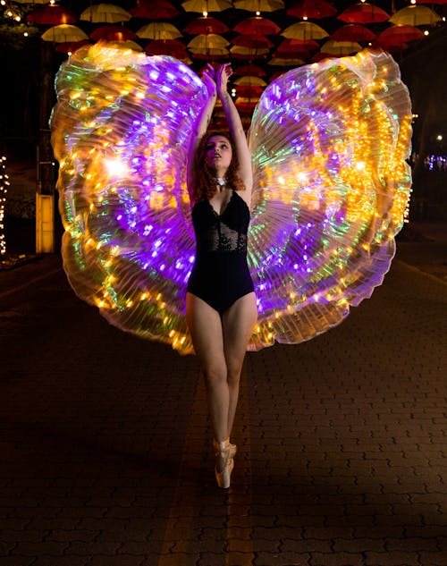A Ballerina Wearing a Costume with Colorful Illuminated Cape
