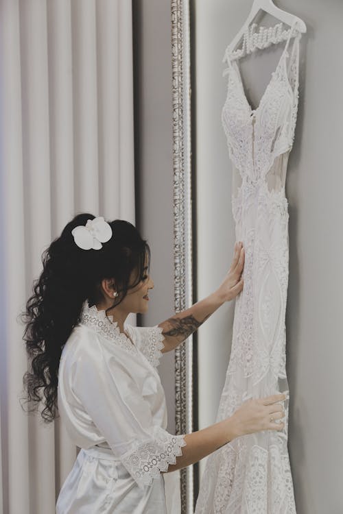 Woman Standing near Wedding Dress on Wall