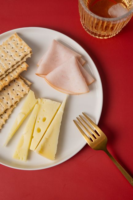 A gourmet snack plate with cheese, ham, and crackers, perfect for sophisticated dining.