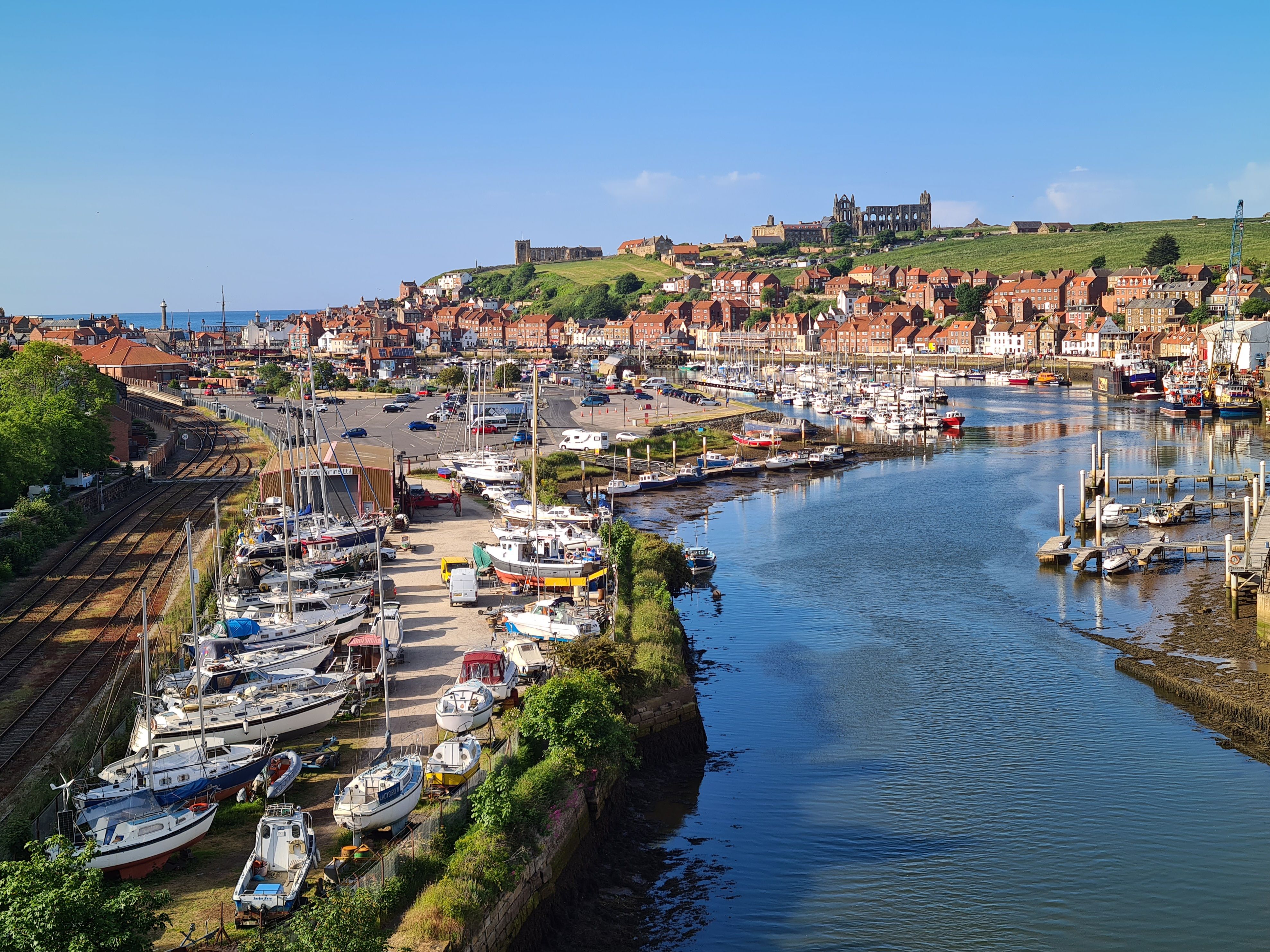Whitby from above — the River Esk winding past the marina and town, with the abbey ruins on the East Cliff.