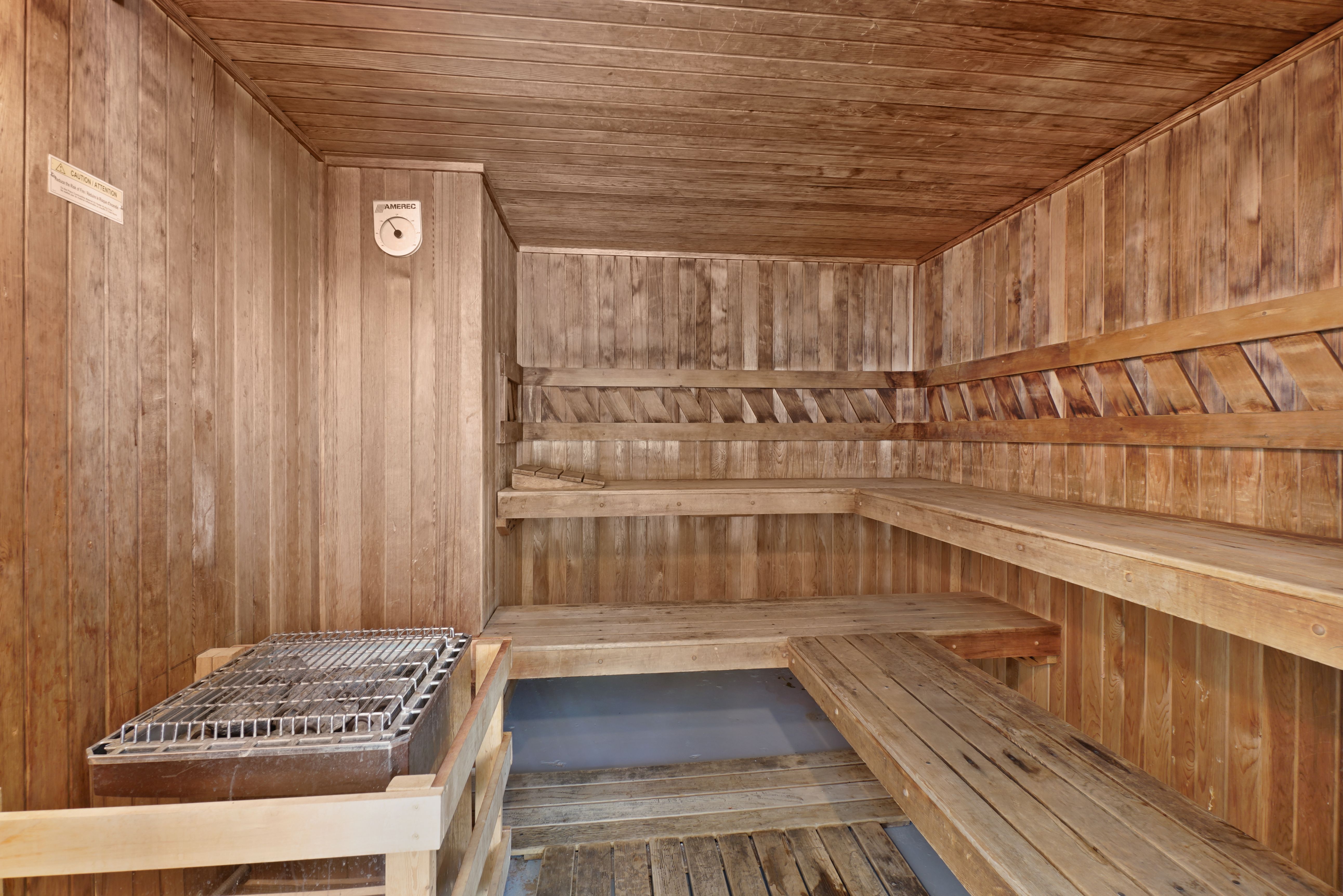 Empty wooden sauna interior with benches and heater