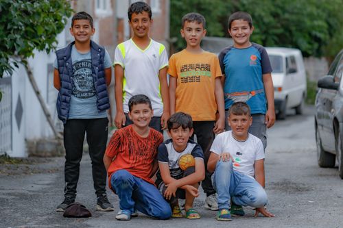 Free Seven boys posing happily together on a street, showcasing friendship and joy. Stock Photo