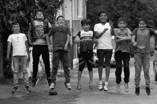 Free A group of boys jumping together on a city street, expressing joy and friendship. Stock Photo