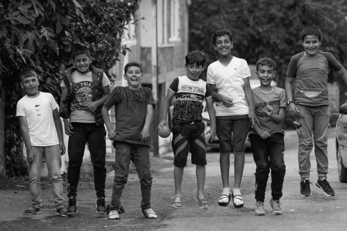 Free A joyful group of young boys jumping and smiling together on a street. Stock Photo