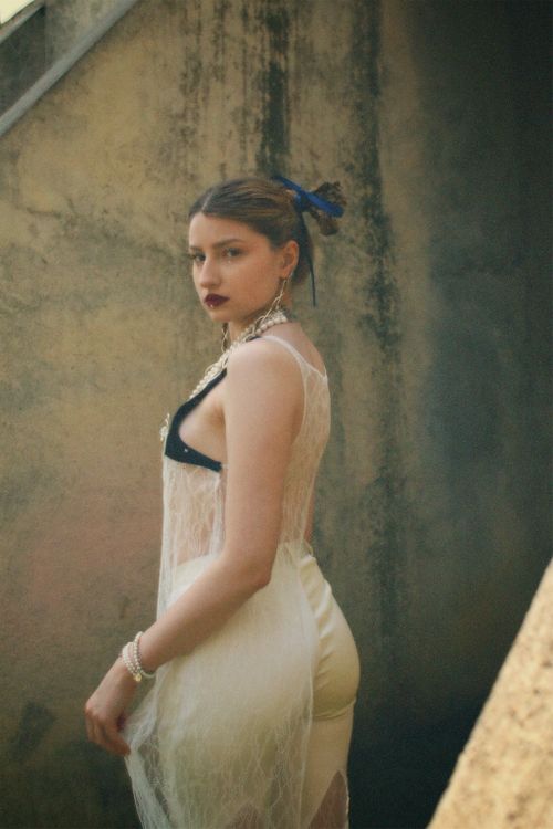 Free Stylish woman in elegant white attire posing against a textured urban wall. Stock Photo