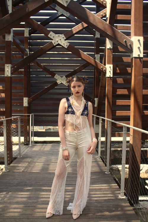Free Stylish woman posing in a modern architectural setting, wearing white lace and blue crop top. Stock Photo