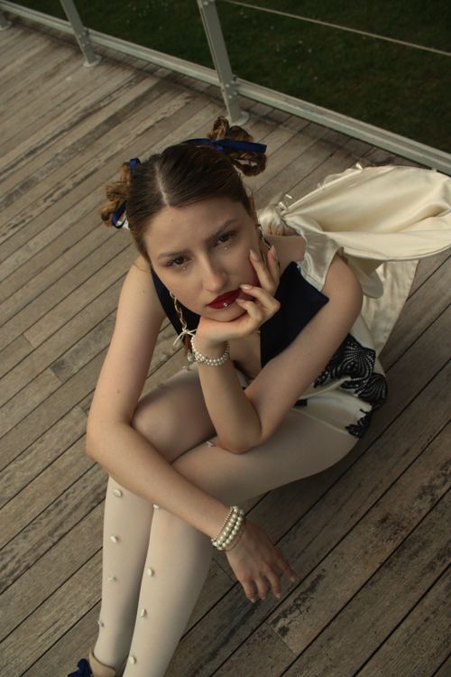 Free Fashionable woman poses thoughtfully on a wooden deck, captured in a high-angle shot. Stock Photo
