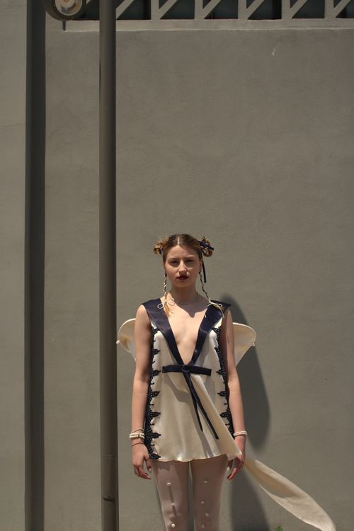 Free Stylish woman posing against a wall in urban setting, sunlit scene. Stock Photo