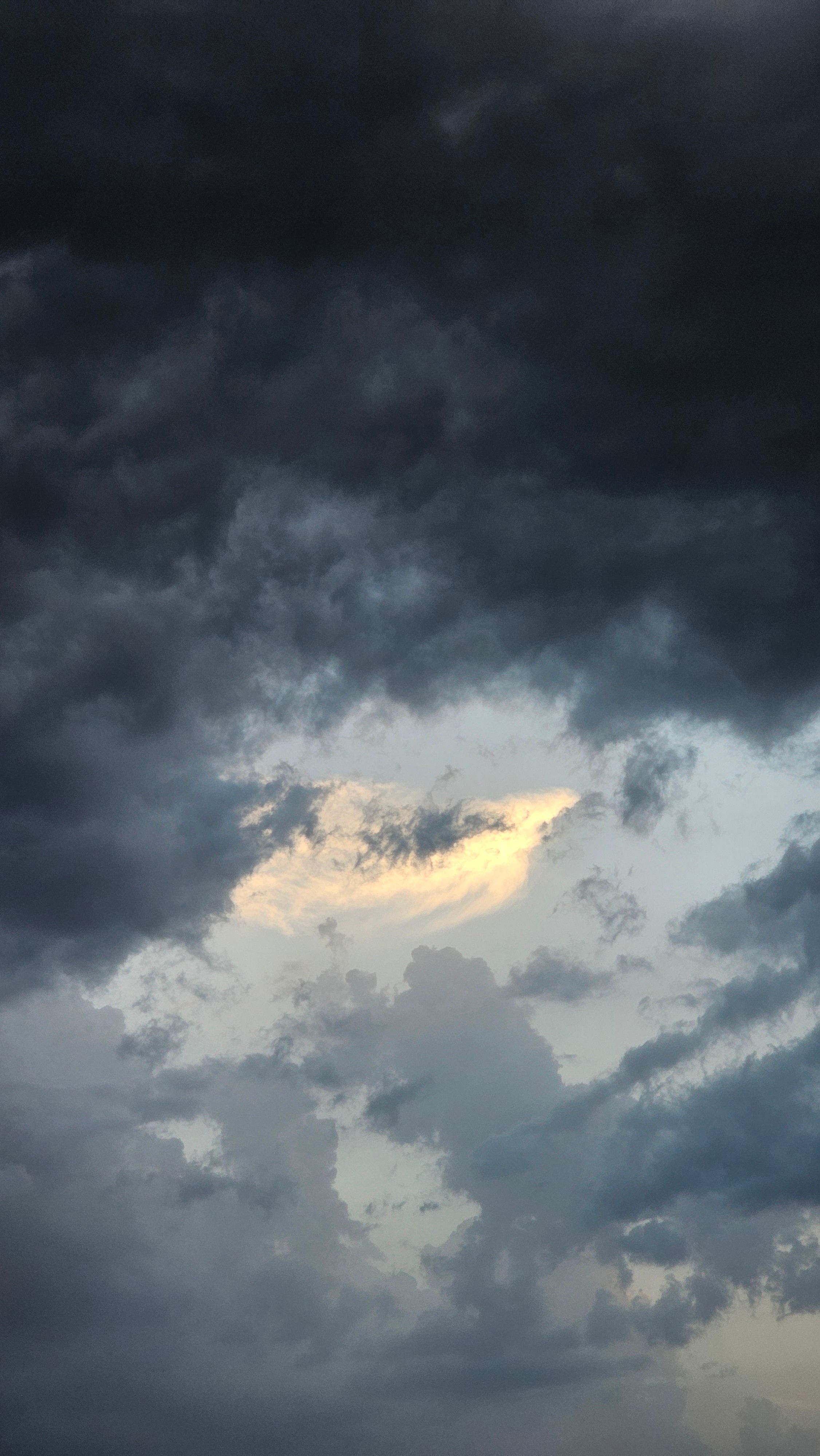 Fotomural Una vista impresionante de un cielo dramático con nubes oscuras y un destello de luz del sol que se filtra.