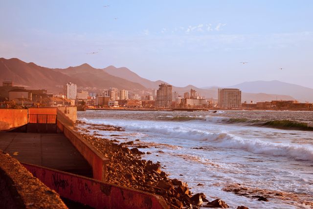 Stunning sunset over Antofagasta coastline, featuring urban landscape and rocky beach.