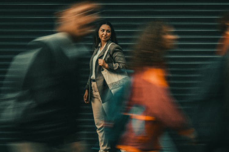 Pedestrians Passing By Woman Standing On Street 