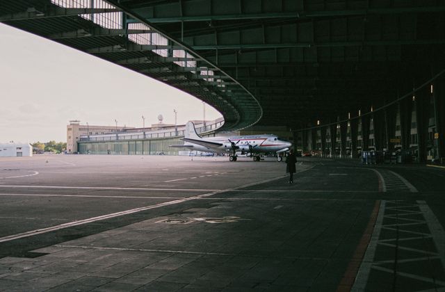A classic aircraft parked inside an iconic Berlin hangar, showcasing aviation history. — arriving in Berlin