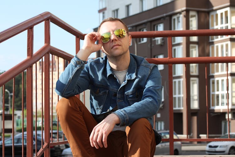 Man Wearing Reflective Sunglasses Sitting On Staircase In City