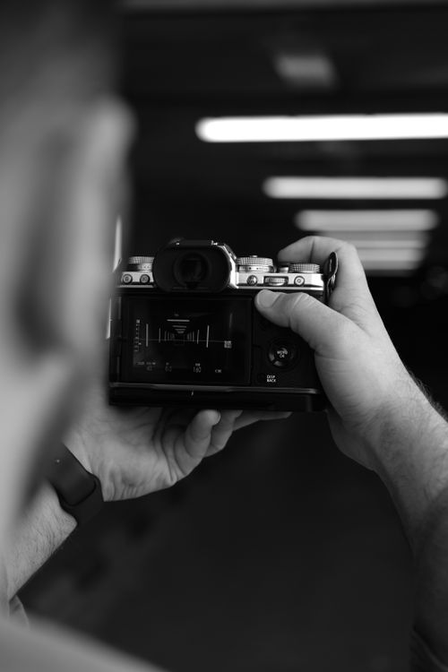 Free Black and white close-up of hands holding a camera in a corridor. Stock Photo
