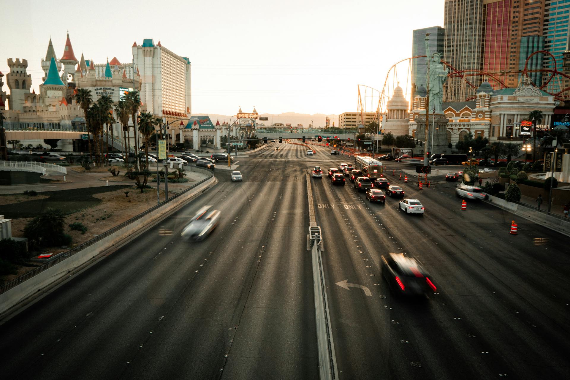 Evening traffic flows on a vibrant Las Vegas street with iconic casino architecture.