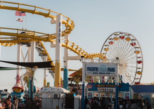 Free Vibrant amusement park scene at Santa Monica Pier with roller coaster and Ferris wheel in view. Stock Photo