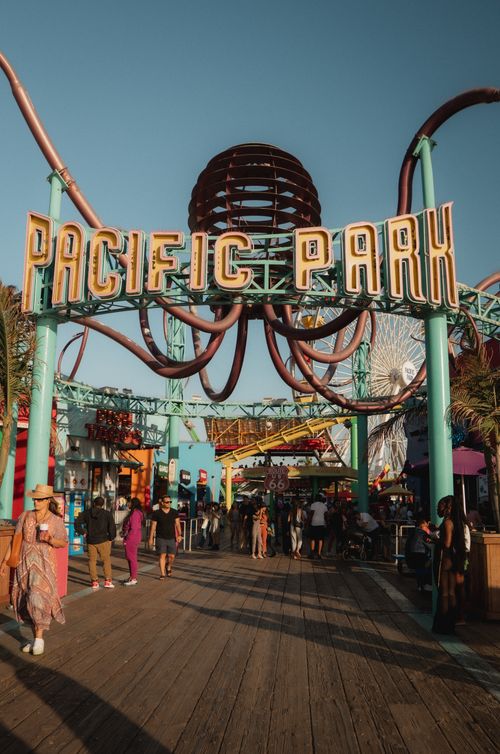 Free Crowds gather at Pacific Park entrance on Santa Monica Pier, showcasing vibrant atmosphere at dusk. Stock Photo
