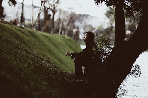 喫煙中に木の下に座っている男