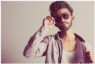 一位戴着墨镜、留着胡须的时尚男子在室内摆着姿势