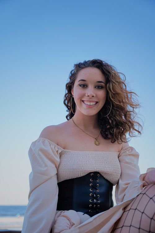 Free Fashionable young woman in a corset smiling at the beach on a sunny day. Stock Photo