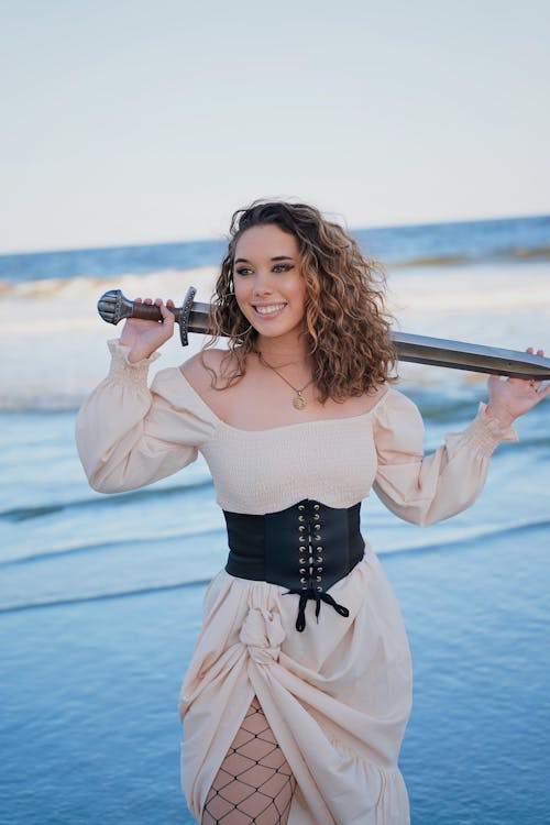 Beautiful Woman in Warrior Costume Posing with Sword on Beach