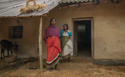 Women in Traditional Clothing Standing in Village House Entrance