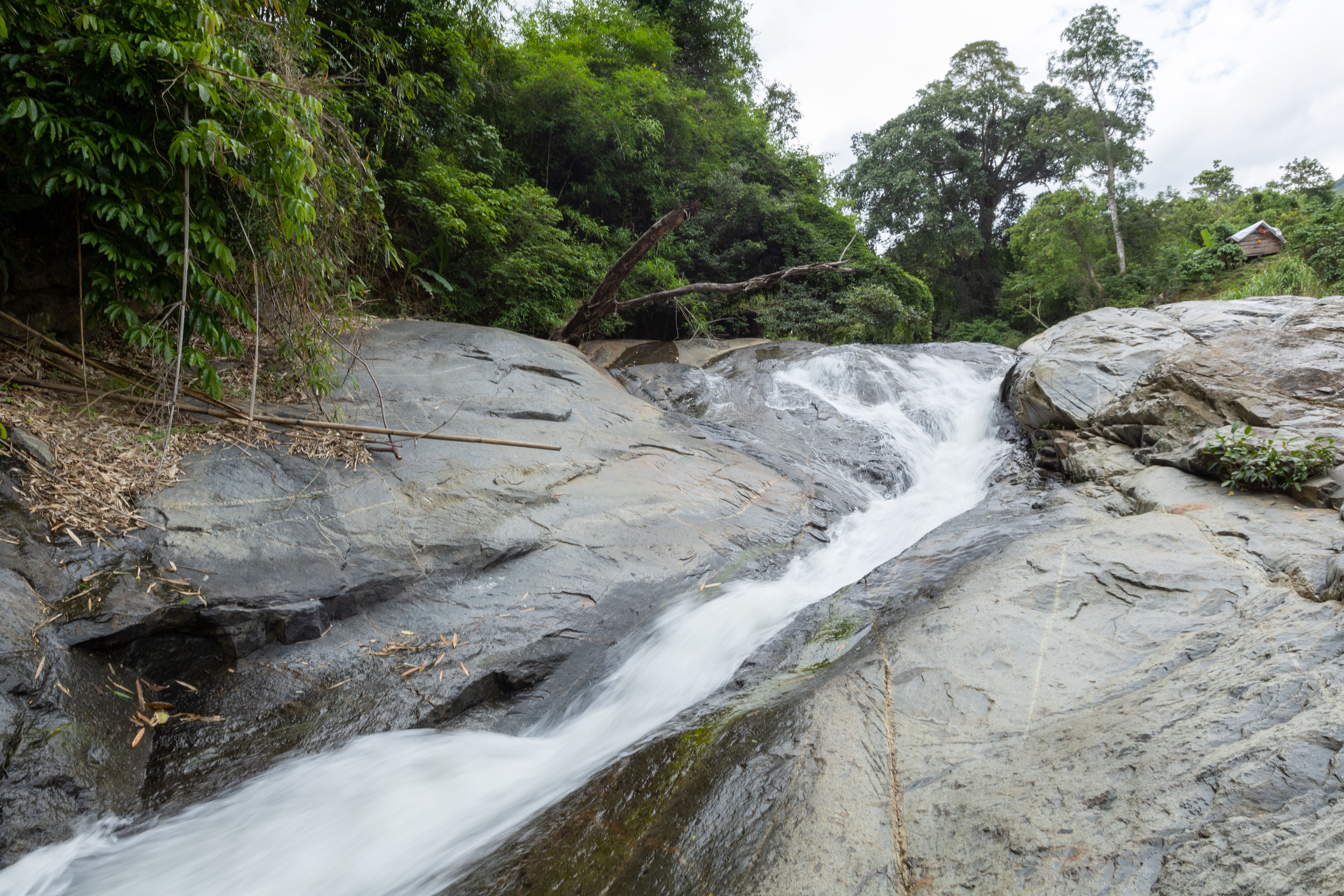 A waterfall is flowing over rocks in the jungle · Free Stock Photo