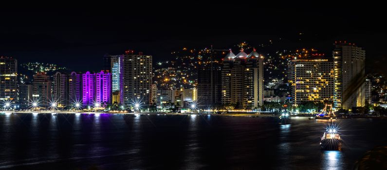 A breathtaking aerial view of Acapulco's illuminated skyline at night.
