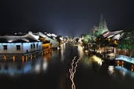 在宁静的夜间景观中，一条平缓流动的河流沿岸展示着历史悠久的建筑，上面带有淡淡的条纹