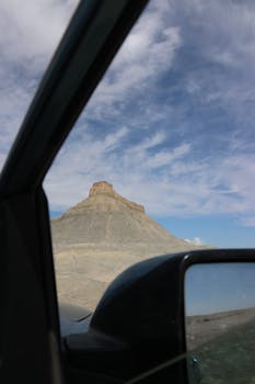 Capture of Utah's striking desert formations through a car window during the day.