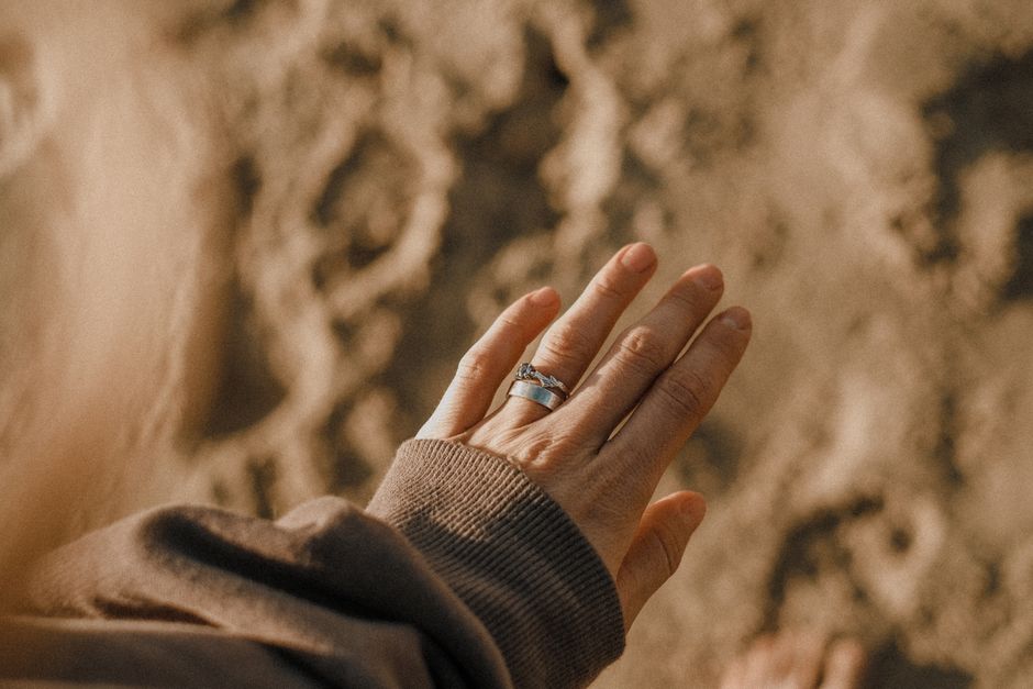 A woman's hand with rings, capturing the essence of a sandy beach outing. Sunlit and serene.