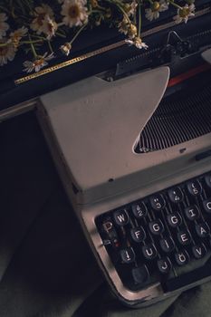 Close-up of a vintage typewriter with daisies, evoking a retro and nostalgic feel.