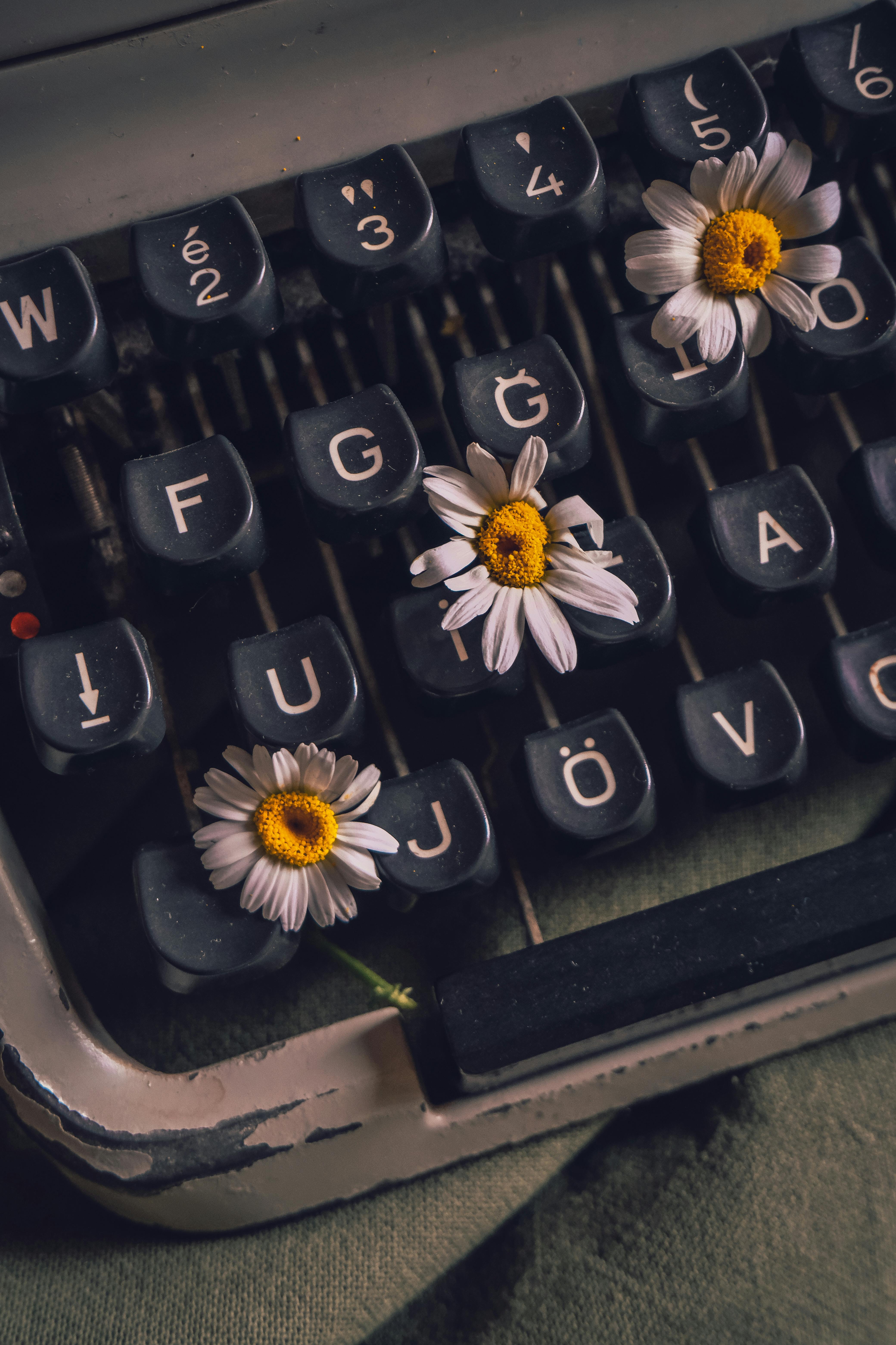 a close up of a retro typewriter with flowers