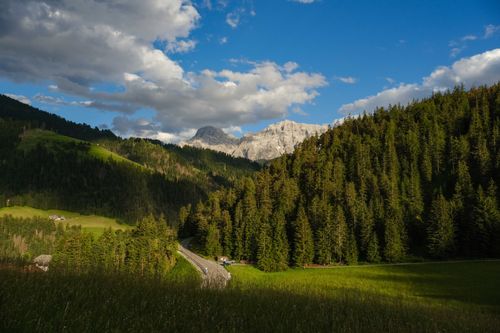 Free Breathtaking view of forested mountains with a winding road under a vivid blue sky. Stock Photo
