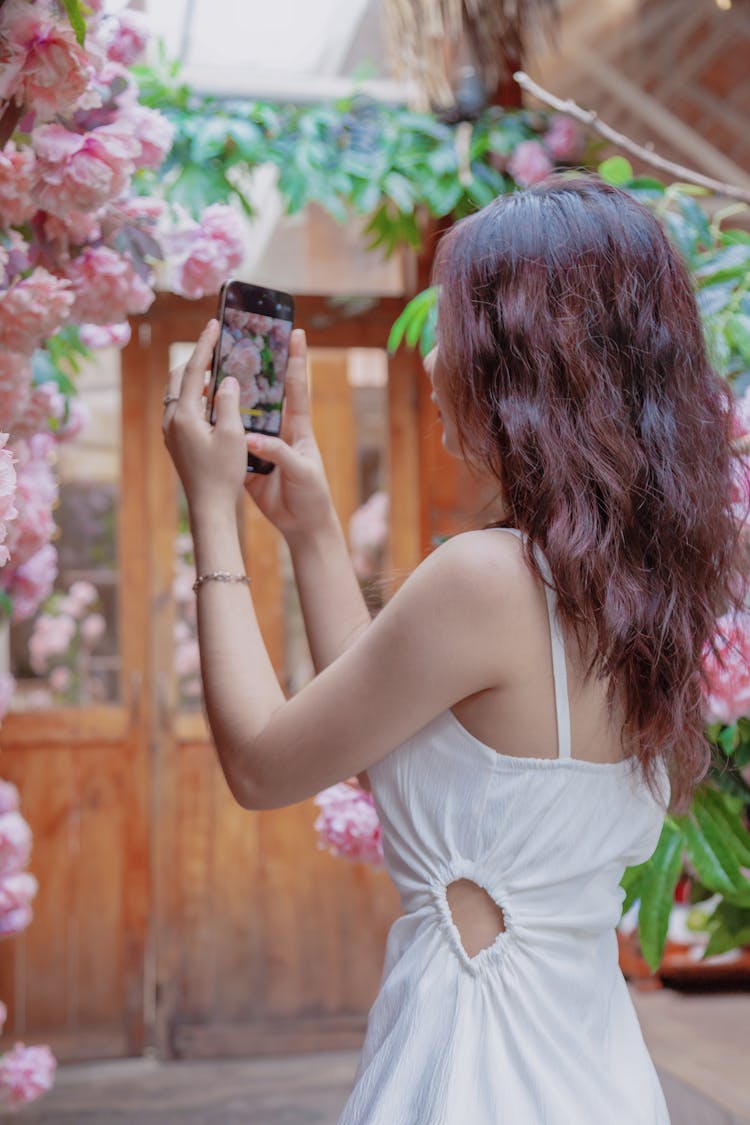 Young Woman Taking A Picture Of Flowers With A Smartphone 