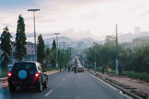 View of a busy urban street during evening with vehicles and pedestrians.