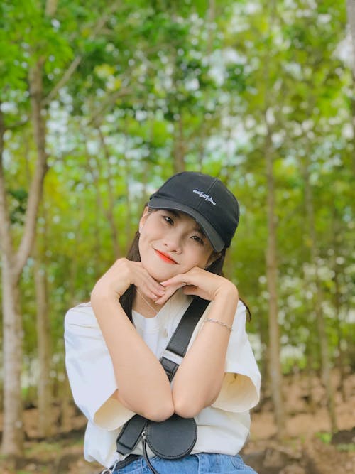 Young Woman in a T-shirt and Cap Standing Outside 