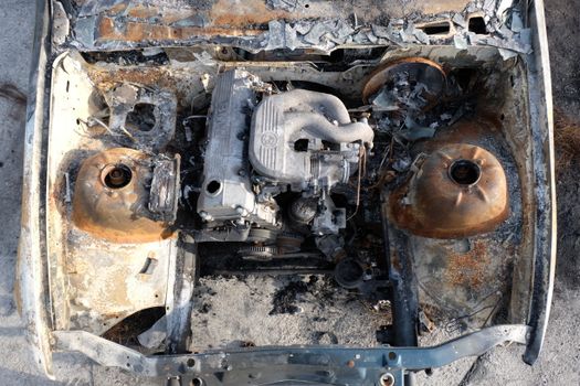Aerial view of a burnt-out engine in an abandoned car, showcasing rust and decay.