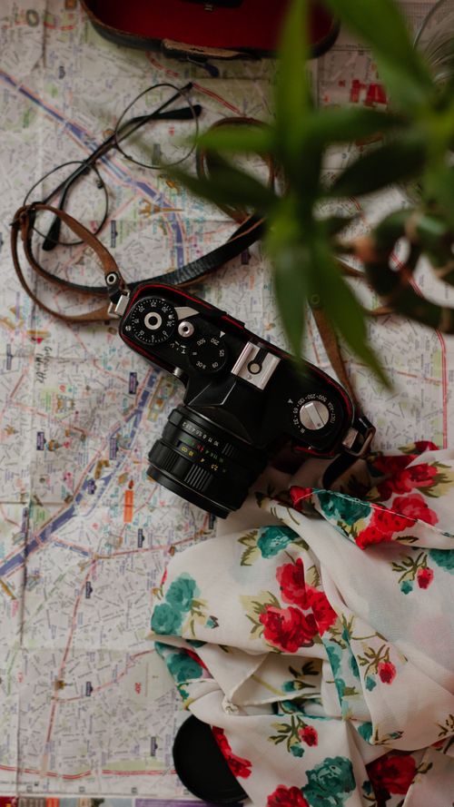 Free Flat lay of vintage camera on map with floral scarf, evoking travel and nostalgia. Stock Photo
