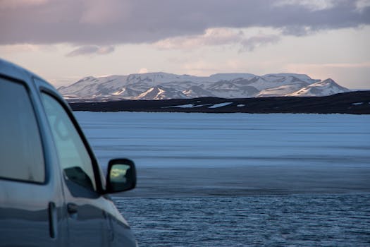 Stunning winter view of Icelandic mountains and snowy terrain with a parked vehicle.