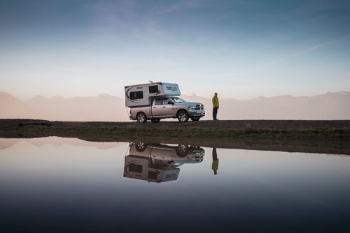 Free Discover tranquility with a camper van by a reflective lake in Iceland's serene landscape. Stock Photo